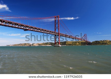 View from under de red bridge of Ponte 25 de abril at Lisbon, Portugal with the lovely blue water and sky with Cristo rei at the background on the south Room for text