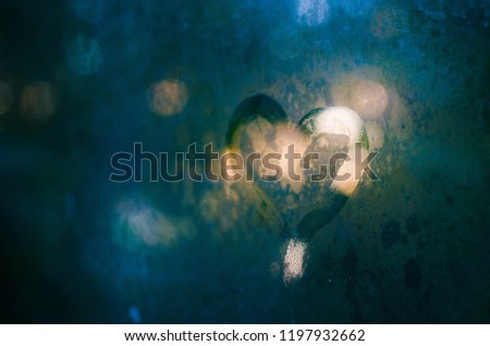 A picture of a heart on a misted glass window in blue tones at dusk. (background)