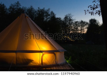 Glamping bell tent glows at night at forest Royalty-Free Stock Photo #1197940960