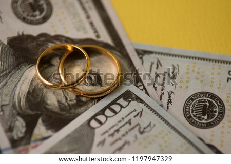 Golden wedding rings on one hundred dollars bill background Royalty-Free Stock Photo #1197947329