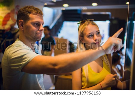 Group people, friends ordering food at the touch screen self service terminal by the electronic menu in the fastfood restaurant Royalty-Free Stock Photo #1197956158