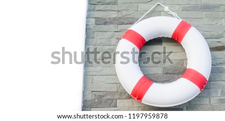Safety first.Red life buoy hanging on wall in swimming pool.