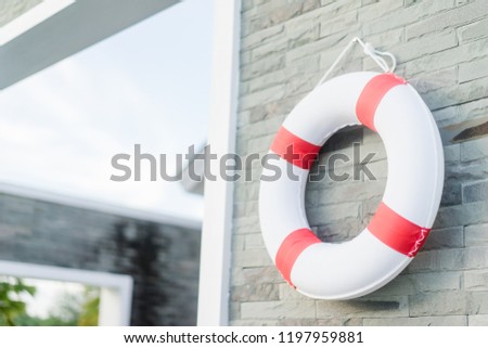 Safety first.Red life buoy hanging on wall in swimming pool.