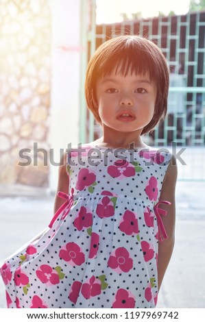Portrait Asian little girl looking at the camera with sunlight in background