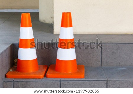 Traffic cone with orange and white stripes on the parking, used for road safety. road traffic cones standing on street on gray tile during road construction works
