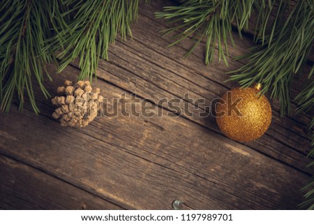 Yellow Christmas ball and pine cone with pine or fir branch on old worn wooden surface