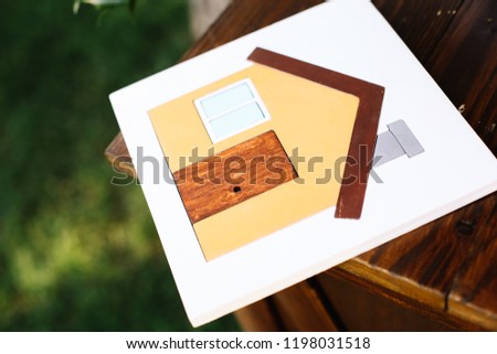 Close-up house made of wooden tangram puzzle over desk on the green grass background