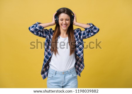Young woman using phone for listening to music on color background.