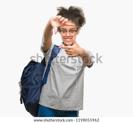 Young afro american student woman wearing headphones and backpack over isolated background smiling making frame with hands and fingers with happy face. Creativity and photography concept.