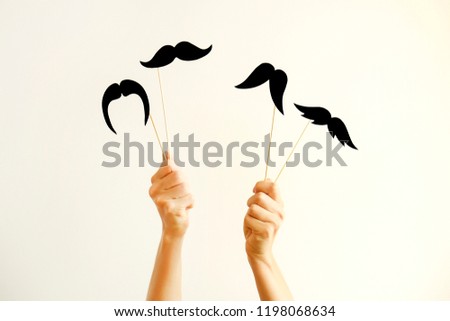 November is month of men health issues and prostate cancer awareness. Young woman holding paper moustache of different style on stick with two hands. Background, close up, copy space