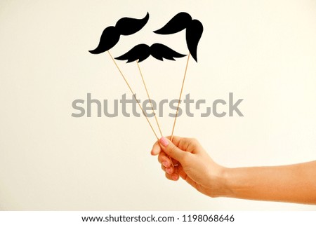 November is month of men health issues and prostate cancer awareness. Young woman holding paper moustache of different style on stick with one hand. Background, close up, copy space.