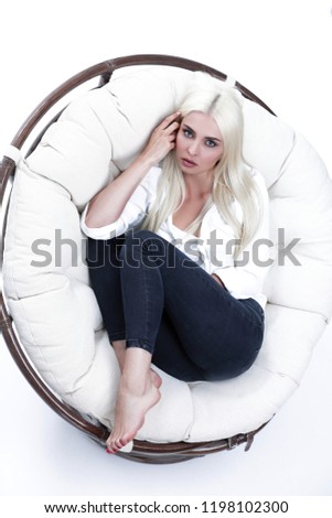 Closeup of a beautiful sad young woman sitting in a large comfortable armchair