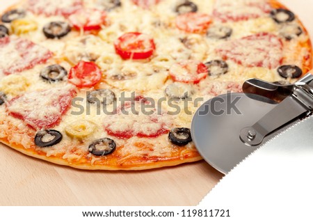 cook pizza on a cutting board with a round knife and spatula