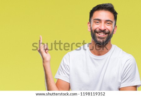 Adult hispanic man over isolated background with a big smile on face, pointing with hand and finger to the side looking at the camera.