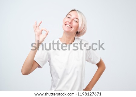 Attractive young adult woman with short colored hair showing ok sign. Expression emotion and feelings concept.
