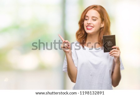 Young beautiful woman holding passport of united states of america over isolated background very happy pointing with hand and finger to the side