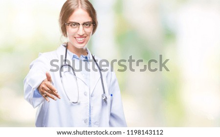 Beautiful young blonde doctor woman wearing medical uniform over isolated background smiling friendly offering handshake as greeting and welcoming. Successful business.