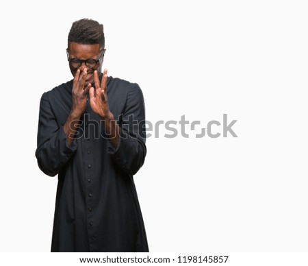 Young african american priest man over isolated background smelling something stinky and disgusting, intolerable smell, holding breath with fingers on nose. Bad smells concept.