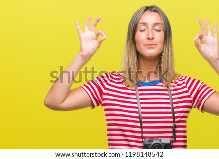 Young beautiful woman taking pictures using vintage photo camera over isolated background relax and smiling with eyes closed doing meditation gesture with fingers. Yoga concept.