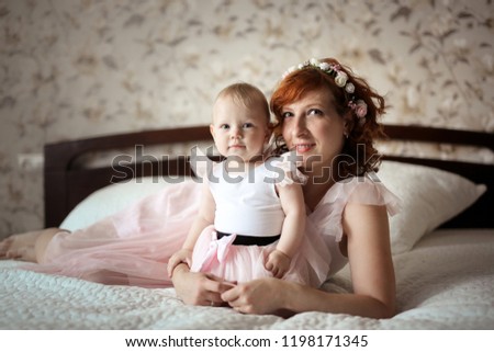 gentle mother and daughter on the bed in a real room, the concept of motherhood and affection
