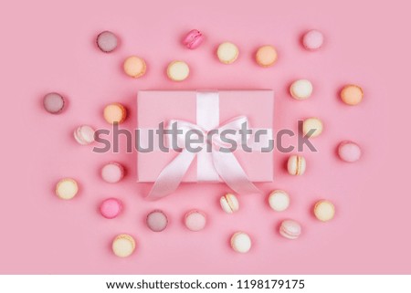 Gift box and macarons on pink background with copy space to write.