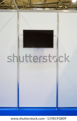 Exhibition stand design equipment. Booth template, Empty exhibition kiosk, with copy space, futuristic interior suspending lighting fixtures, shelves and tv screen.