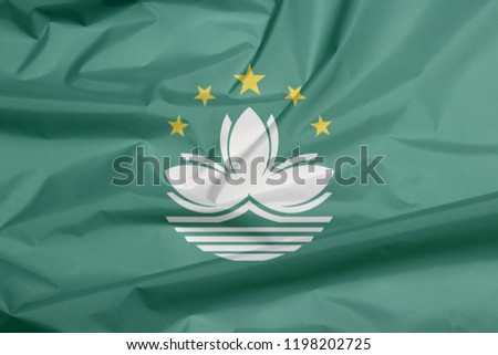 Fabric flag of Macau. Crease of Macau flag background, green with a lotus and stylised Governor Nobre de Carvalho Bridge and water in white, and five gold star. 