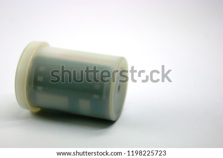 old used roll of 35mm film inside the white plastic canister isolated on white background