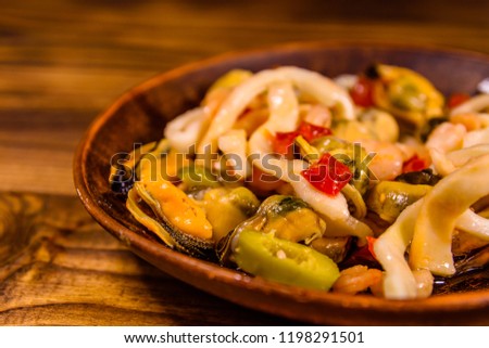 Ceramic plate with different sea food and olives on rustic wooden table