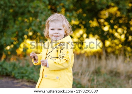 Cute little toddler girl making a walk through autumn park. Happy healthy baby enjoying walking with parents. Sunny warm fall day with child. Active leisure and activity with kids in nature