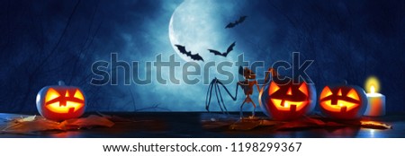Halloween holiday concept banner. Pumpkins over wooden table at night scary, haunted and misty forest