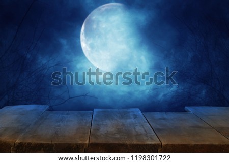 Halloween holiday concept. Empty rustic table in front of scary and misty night sky and full moon background. Ready for product display montage