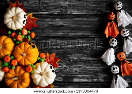 Top view of white and yellow ghost pumpkins with Colorful Autumn leaves on a black wooden table background. halloween concept.