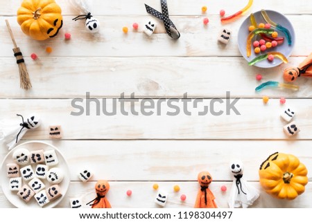 Top view of white and yellow ghost pumpkins with bat spider mummy jelly worm and gift box on white wooden background. halloween concept.