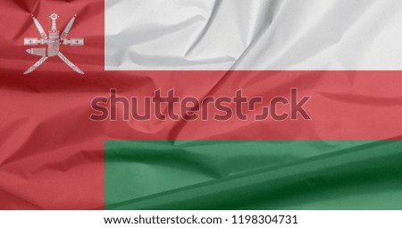 Fabric flag of Oman. Crease of Omani flag background, white red and green; with a vertical red stripe, charged with the National emblem of Oman.
