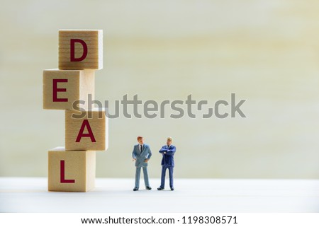 Business deal / financial agreement concept : Miniature figurine two businessmen e.g CEO, CFO talk or negotiate on a company or corporate financial transaction, depicts buyer & seller bargain on goods Royalty-Free Stock Photo #1198308571