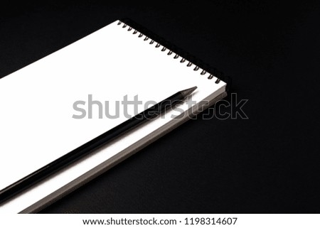 Opened clean notebook or sketchbook with pencil on black background