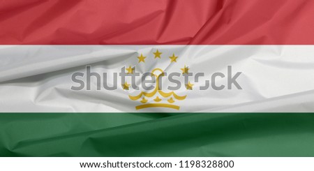 Fabric flag of Tajikistan. Crease of Tajik flag background, red white and green; charged with a crown surmounted by an arc of seven stars at the center.