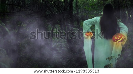 Portrait of a dead girl on Halloween in a gloomy forest. Dead girl with Jack-o-lantern in a misty forest at night.