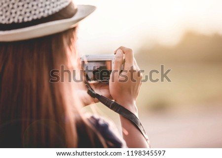 The rear view of a woman holding a camera by her interest.