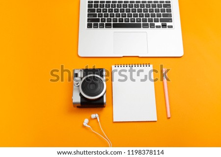 Creative feminine workplace with stationery supplies, laptop and camera. Travel or photography planning. Freelance, work at home or blogging concept. Bright colors. Copy space for your text.