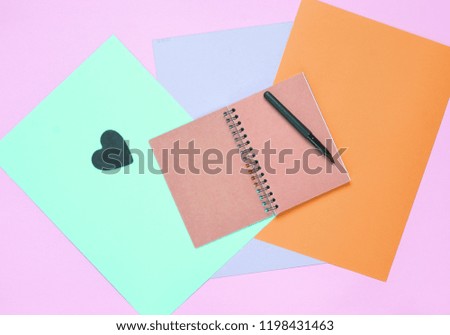 Notepad with pen on colored paper background. Girly diary. Top view.
