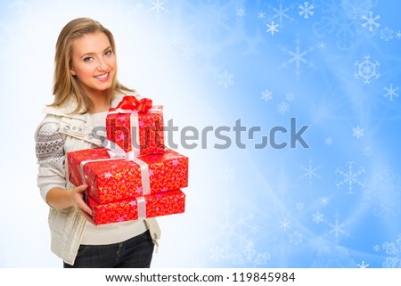 Young smiling girl with gift boxes on winter background