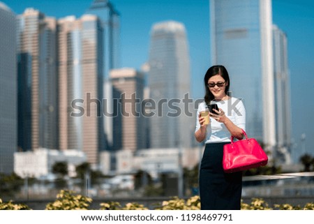 Business woman walking in city with coffee and smartphone on hand