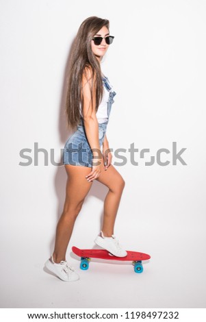Happy young woman in sunglasses with skateboard over white background