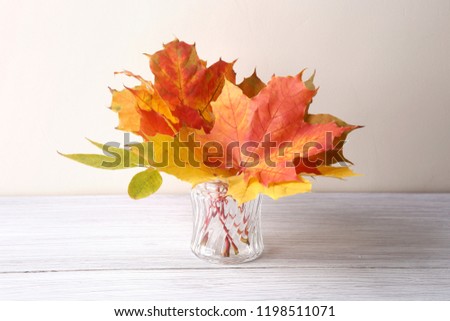 Maple leaves in vase in interior. Autumn colorful composition as decoration indoor.
