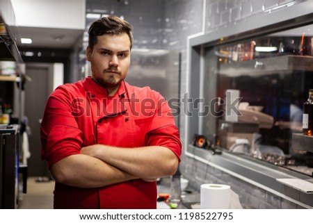 Portrait of male cook chef in kitchen in a restaurant with red clothes