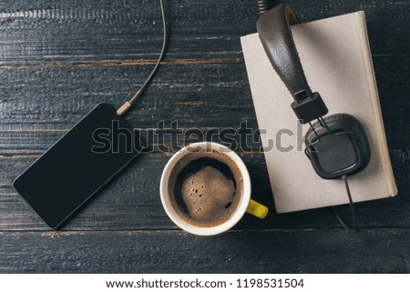 Audio book concept. Headphones, coffee and book over wooden table