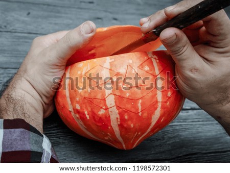 The concept of Halloween. Men's hands cut off the top of the pumpkin.
