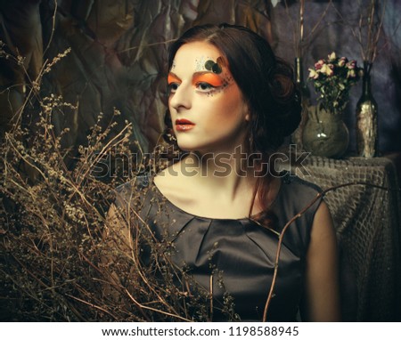 Beauty and art concept: Young woman with bright make up with dry branches